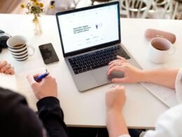 Eine Person arbeitet konzentriert an einem Laptop auf einem Schreibtisch mit moderner Büroausstattung.