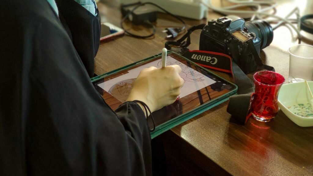 Eine Person sitzt an einem Schreibtisch und schreibt mit einem Stift auf einem Tablet in einer modernen Arbeitsumgebung.