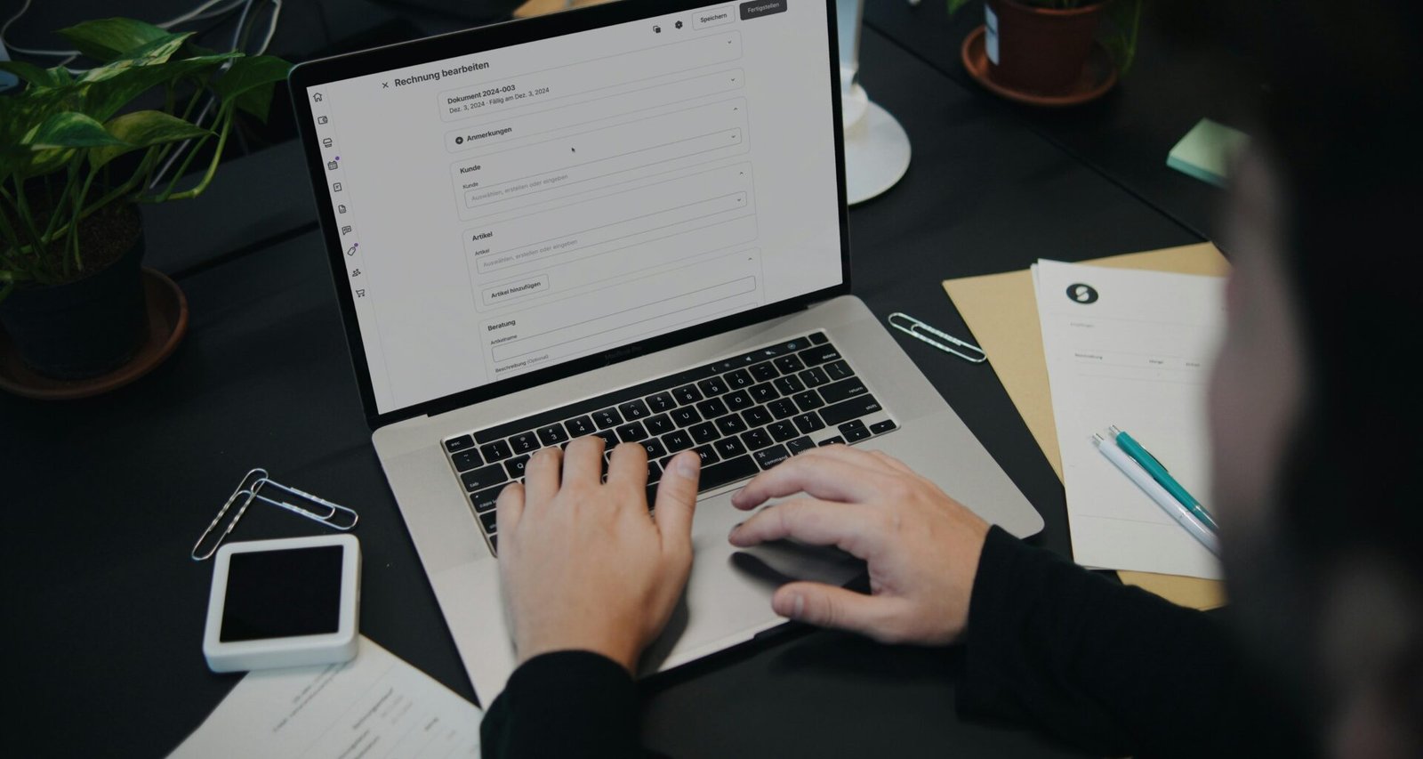 Eine Person sitzt an einem Schreibtisch und arbeitet an einem Laptop-Computer in einem modernen Büro.