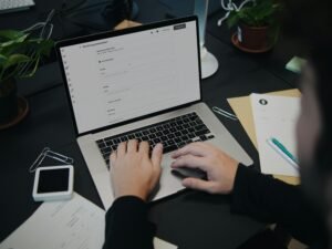 Eine Person sitzt an einem Schreibtisch und arbeitet an einem Laptop-Computer in einem modernen Büro.