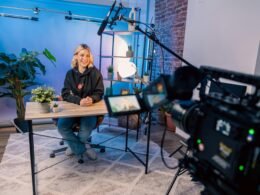 Eine Person sitzt an einem Tisch und arbeitet in einem modernen, hellen Raum, Fokus auf die Arbeitsumgebung.