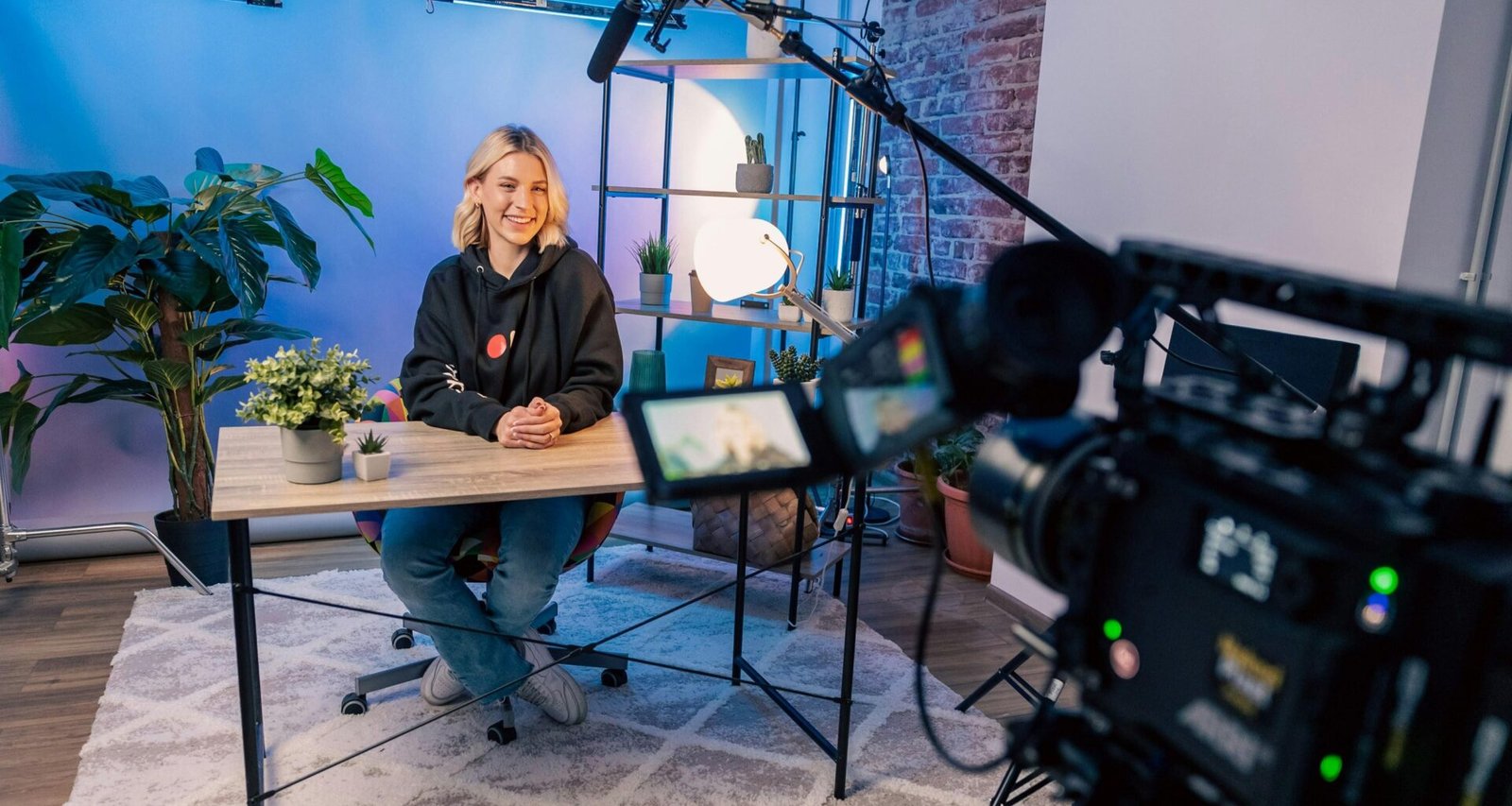 Eine Person sitzt an einem Tisch in einem modernen Raum und arbeitet konzentriert an einem Laptop.