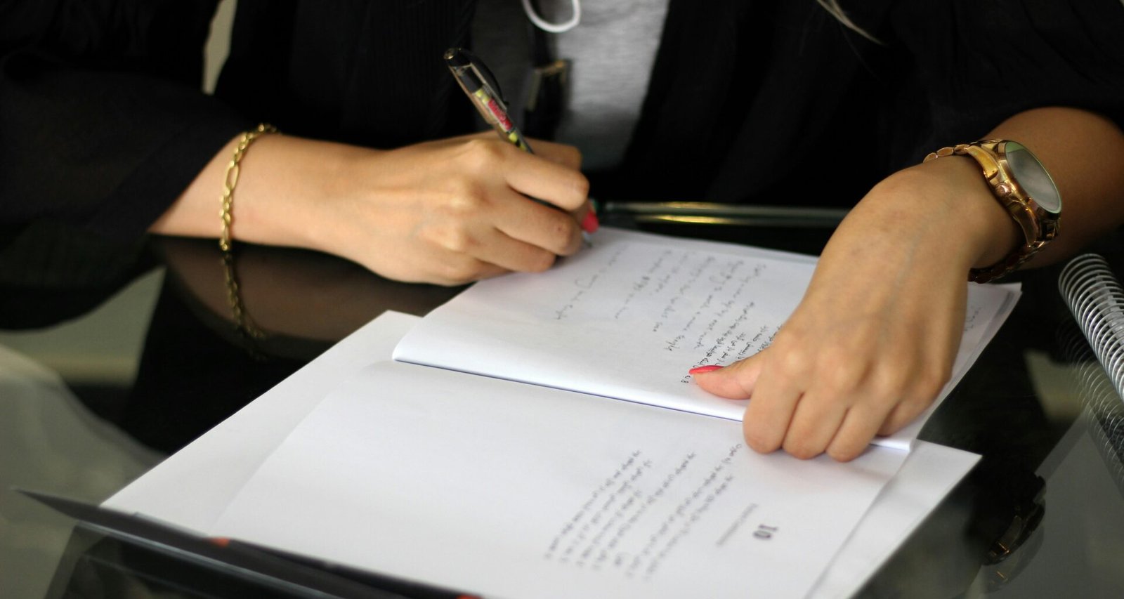 Person hält einen Stift und schreibt Notizen auf ein Blatt Papier, Nahaufnahme der Hand und des Schreibprozesses