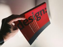 Eine Person hält ein Buch in der Hand, das als Symbol für Wissen und Bildung im Kontext von Technologie und Online-Marketing steht.