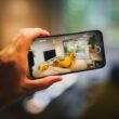 Person fotografiert ein modernes Wohnzimmer mit dem Smartphone in einer hellen, einladenden Umgebung