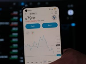 Eine Person hält ein Smartphone in der Hand, Fokus auf das Gerät vor neutralem Hintergrund.