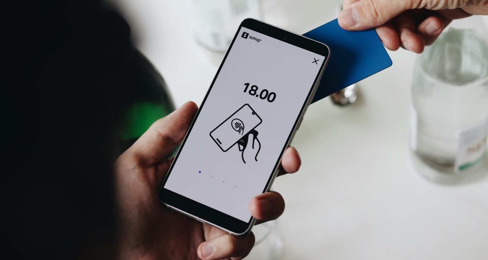 Eine Person hält ein Smartphone in der Hand und nutzt das Mobilgerät aktiv im urbanen Umfeld