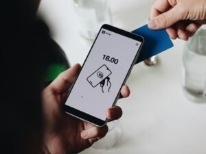 Eine Person hält ein Smartphone in der Hand und nutzt das Mobilgerät aktiv im urbanen Umfeld