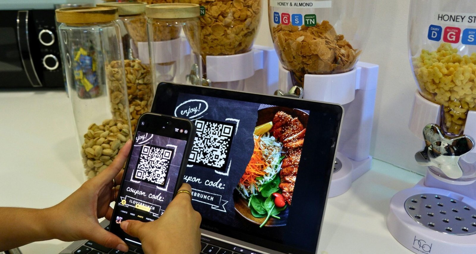 Person arbeitet am Tisch gleichzeitig mit einem Smartphone und einem Laptop, beide Geräte nebeneinander platziert