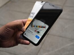 Person hält ein iPhone und eine Kreditkarte in der Hand, bereit für eine mobile Online-Zahlung