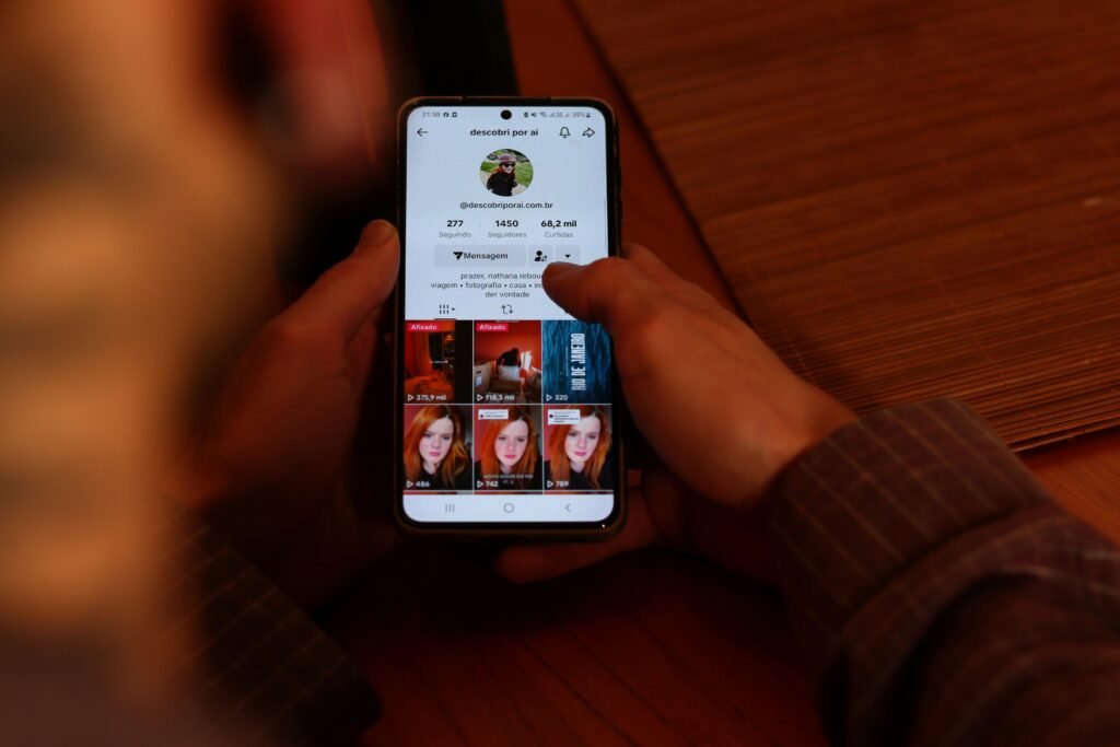 Eine Person hält ein Smartphone, auf dessen Bildschirm mehrere Bilder angezeigt werden, Fokus auf mobile Bildergalerie.