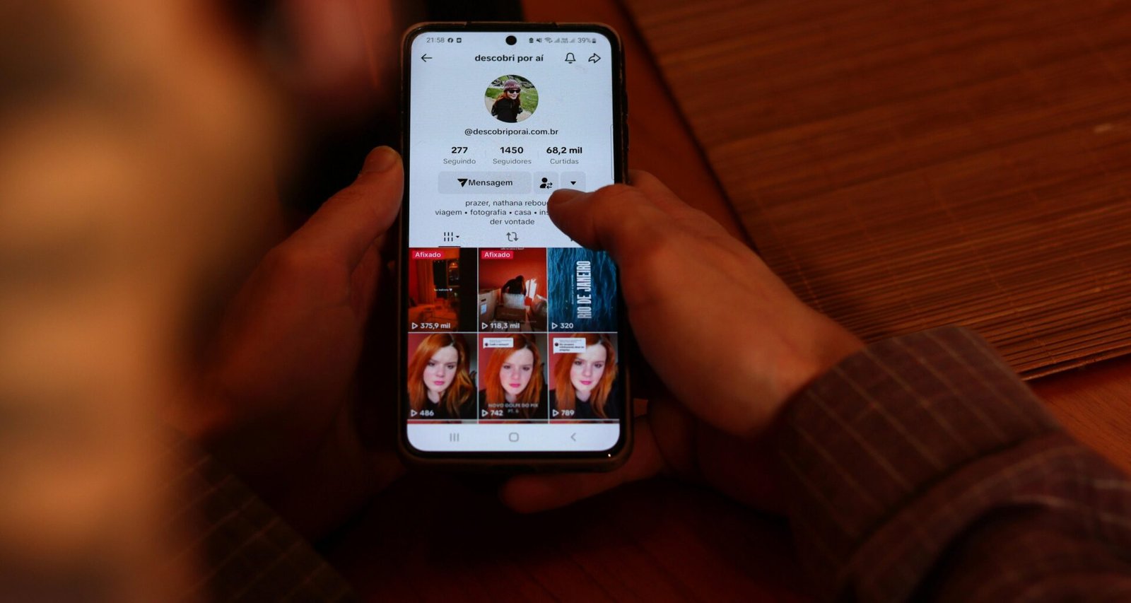 Eine Person hält ein Smartphone, auf dessen Bildschirm mehrere Bilder angezeigt werden, Fokus auf mobile Bildergalerie.