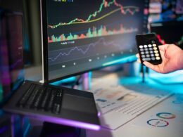 Eine Person bedient einen Computer mit einer Fernbedienung, Fokus auf Hand und Fernsteuerung im digitalen Arbeitsumfeld.