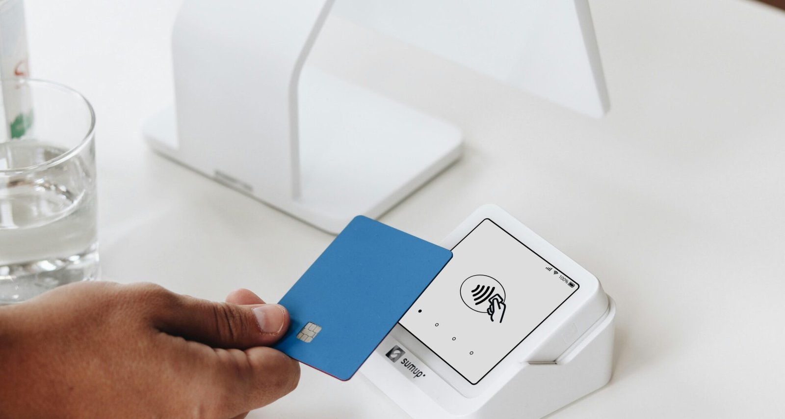 Eine Person hält eine Bankkarte vor einen Laptop, um eine Online-Zahlung oder digitale Transaktion durchzuführen.