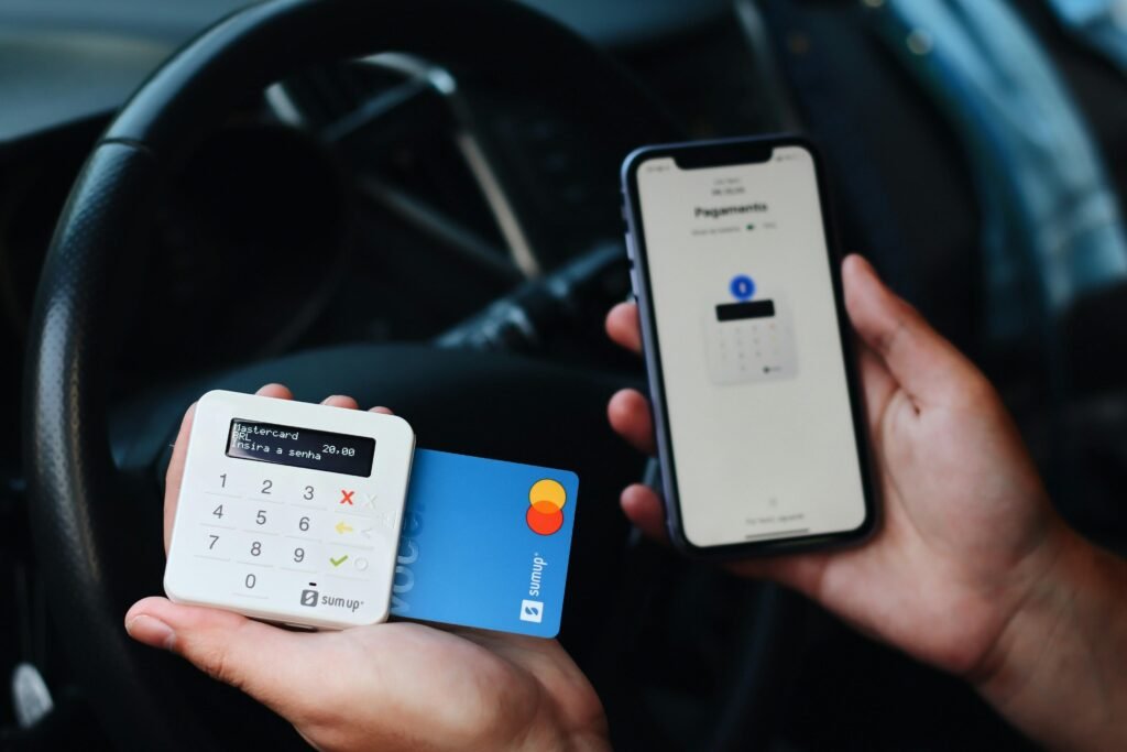 Eine Person hält eine Kreditkarte in der einen und ein Smartphone in der anderen Hand für die digitale Bezahlung.