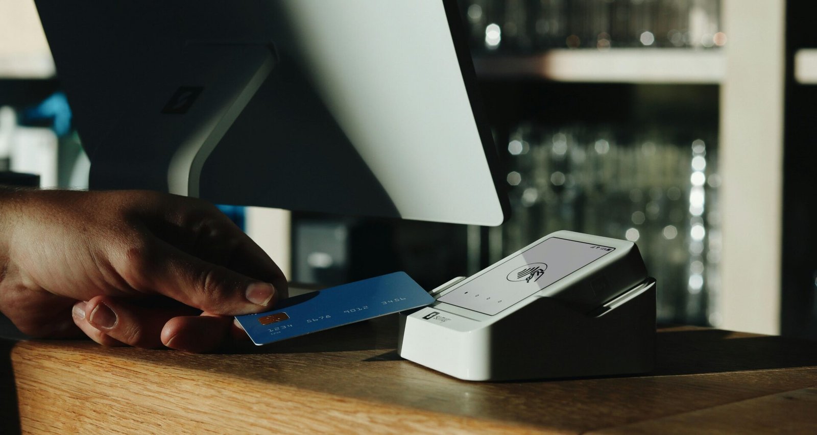 Eine Person hält eine Kreditkarte vor einem Computer, bereit zur Eingabe der Zahlungsdaten für einen Online-Kauf.