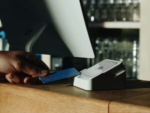 Eine Person hält eine Kreditkarte vor einem Computer, bereit zur Eingabe der Zahlungsdaten für einen Online-Kauf.