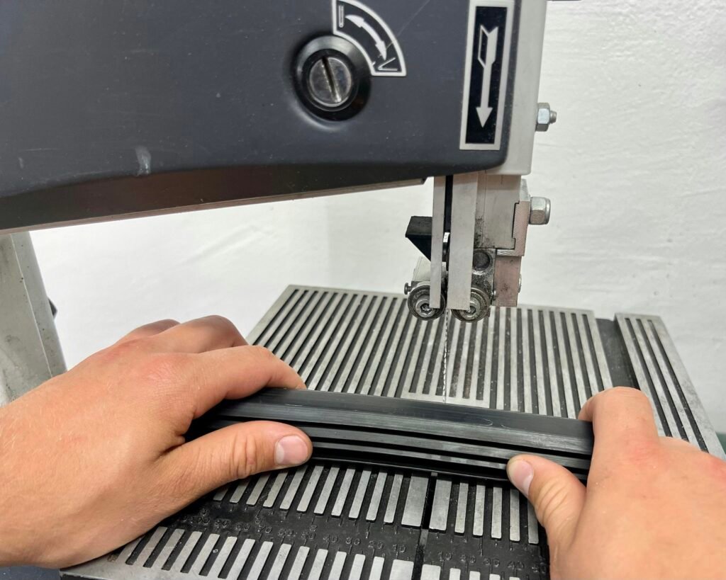 Eine Person verwendet eine Nähmaschine, um ein Stoffstück zu nähen. Die Nahaufnahme zeigt Hände und Stoff beim Nähvorgang.