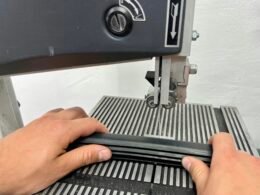 Eine Person verwendet eine Nähmaschine, um ein Stoffstück zu nähen. Die Nahaufnahme zeigt Hände und Stoff beim Nähvorgang.