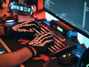 Person trägt einen Skelett-Handschuh und tippt auf einer Computertastatur, kreatives Technologie-Motiv