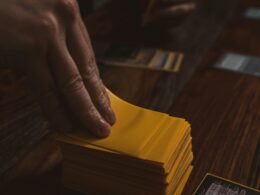 Eine Person hält einen Stapel gelber Karten in der Hand, die symbolisch für Auswahl oder Kennzeichnung stehen.