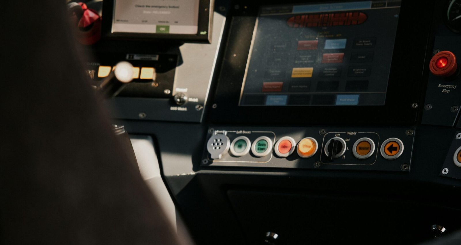 Eine Person sitzt in einem Fahrzeug und nutzt ein übersichtliches Kontrollpanel mit verschiedenen Bedienelementen.