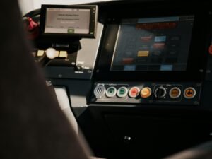 Eine Person sitzt in einem Fahrzeug und nutzt ein übersichtliches Kontrollpanel mit verschiedenen Bedienelementen.