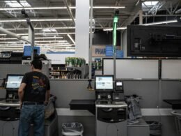 Eine Person steht in einem Raum mit mehreren Computern und technischer Ausrüstung, typische IT-Arbeitsumgebung.