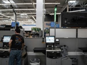 Eine Person steht in einem Raum mit mehreren Computern und technischer Ausrüstung, typische IT-Arbeitsumgebung.