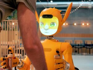 Eine Person steht einem orangefarbenen Roboter gegenüber und interagiert mit ihm in einer modernen Umgebung.