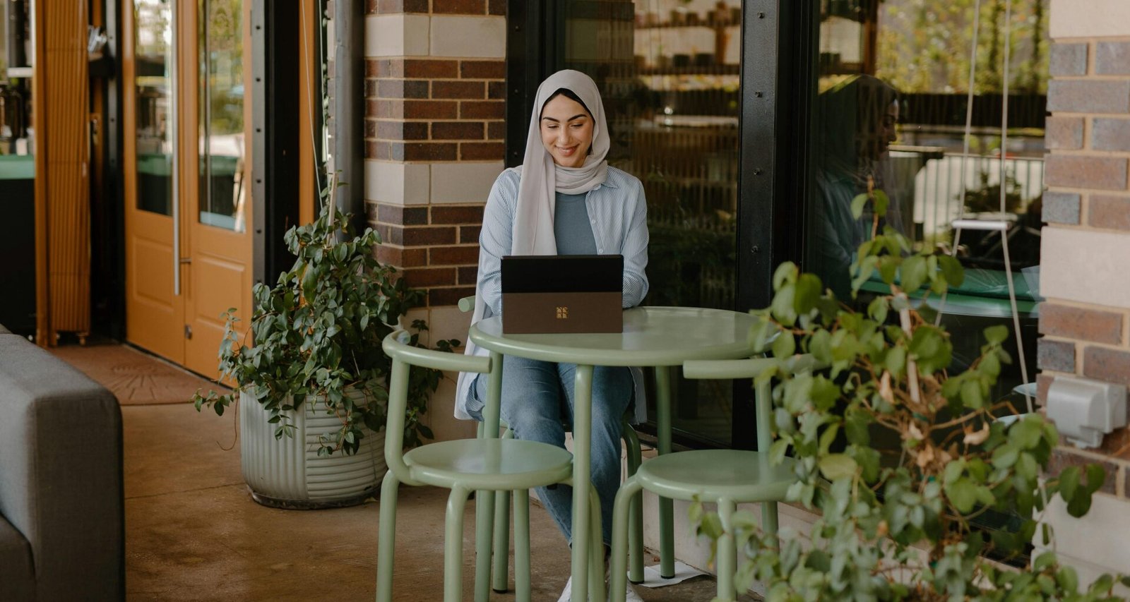Person sitzt an einem Tisch und nutzt einen Laptop für digitale Arbeit, modernes Umfeld mit Technik am Arbeitsplatz.