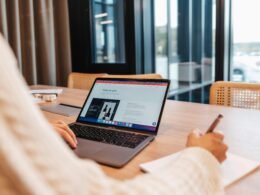 Eine Person sitzt an einem Tisch und arbeitet konzentriert an einem Laptop – Fokus auf digitale Arbeit und Technik.