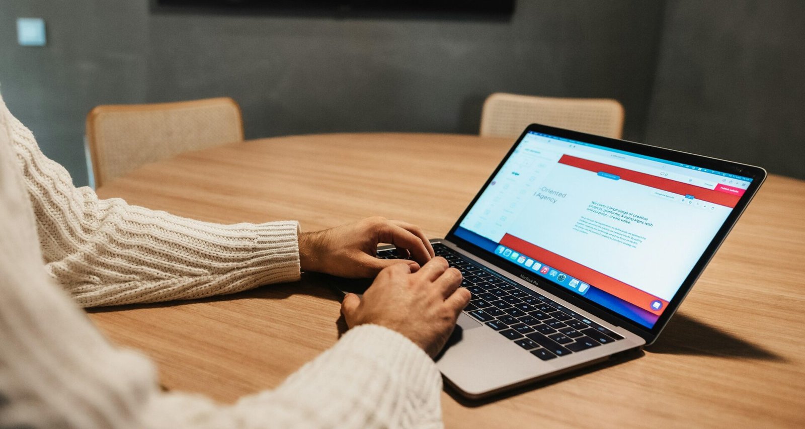 Eine Person arbeitet an einem Tisch mit aufgeklapptem Laptop und konzentriert sich auf den Bildschirm