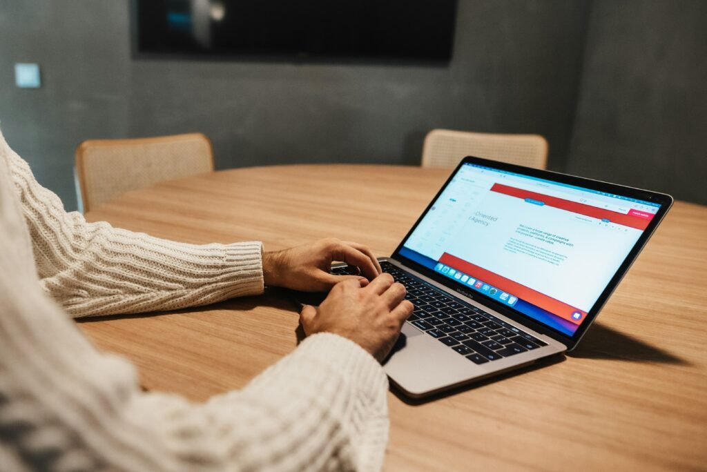 Person sitzt an einem Tisch und arbeitet konzentriert mit einem Laptop, modernes Arbeitsumfeld im Fokus