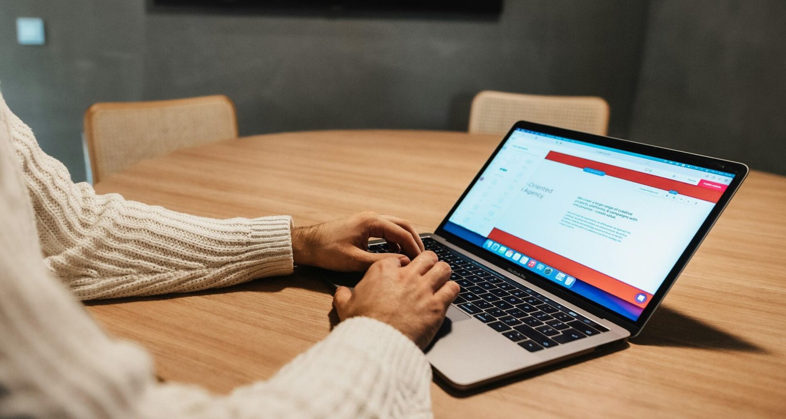 Person sitzt an einem Tisch und arbeitet konzentriert mit einem Laptop, modernes Arbeitsumfeld im Fokus