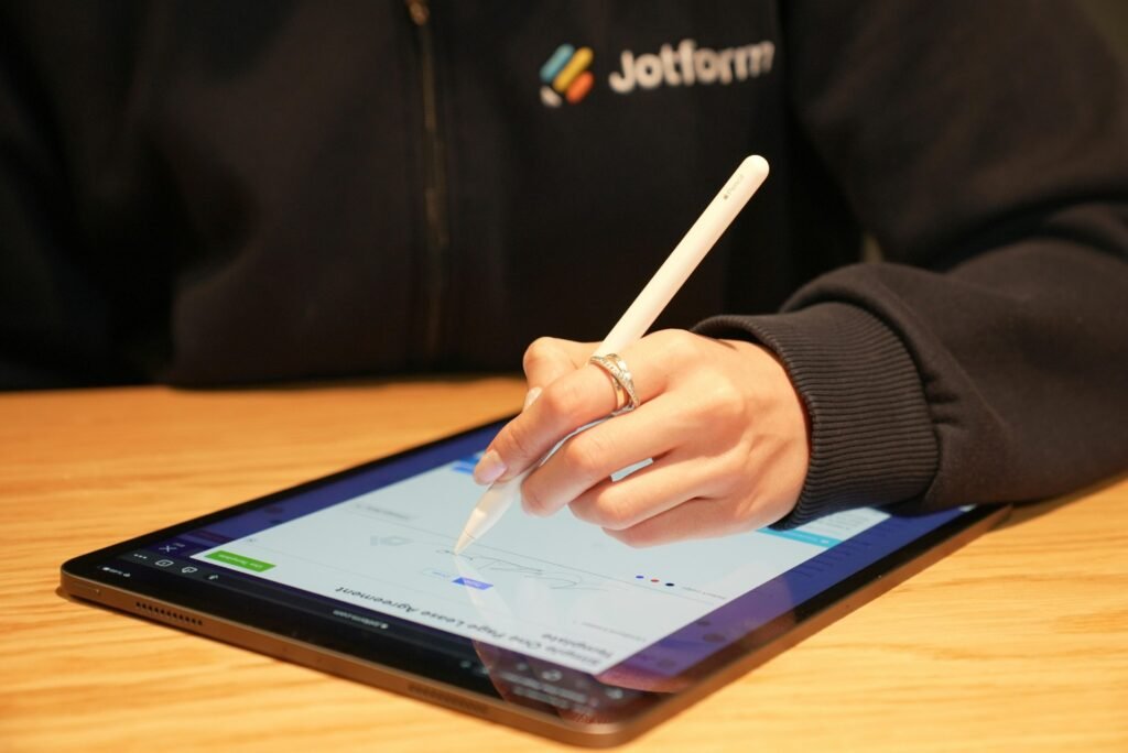 Eine Person schreibt mit einem digitalen Stift auf einem Tablet und erfasst digitale Notizen für die Arbeit oder das Studium.