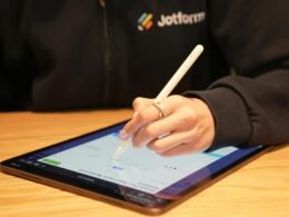 Eine Person schreibt mit einem Stift auf einem Tablet – modernes Arbeiten mit digitalen Notizen und Tools im Büroalltag.