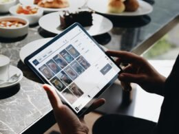 Eine Person sitzt an einem Tisch und arbeitet mit einem Tablet, um digitale Aufgaben effizient zu bearbeiten.