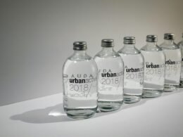 Reihe von Flaschen, jede mit einem individuellen Namen versehen, aufgenommen vor hellem Hintergrund