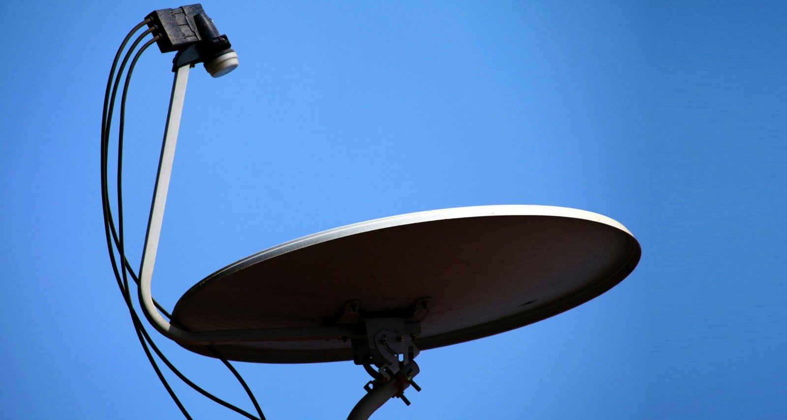 Eine große weiße Satellitenschüssel steht vor einem wolkenlosen blauen Himmel. Moderne Technik für Datenübertragung.