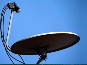 Eine große weiße Satellitenschüssel steht vor einem wolkenlosen blauen Himmel. Moderne Technik für Datenübertragung.