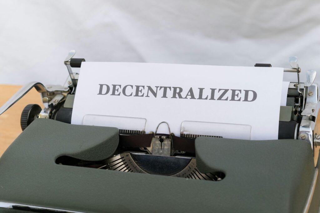 Schreibmaschine mit eingelegtem Papier, auf dem das Wort decentralized steht. Symbolbild für Dezentralisierung und Technologie.