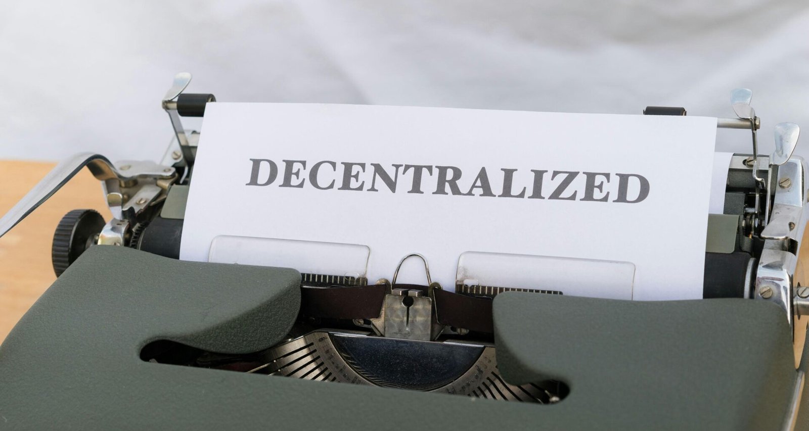 Schreibmaschine mit eingelegtem Papier, auf dem das Wort decentralized steht. Symbolbild für Dezentralisierung und Technologie.