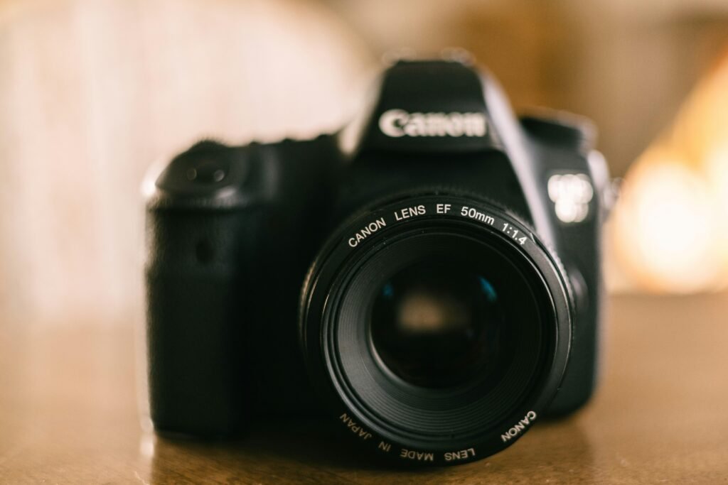 Eine schwarze Kamera steht auf einem hölzernen Tisch. Die Aufnahme zeigt moderne Technik in einer ruhigen Umgebung.