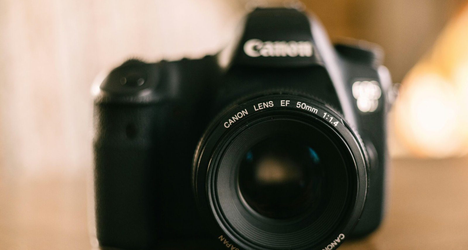 Eine schwarze Kamera steht auf einem hölzernen Tisch. Die Aufnahme zeigt moderne Technik in einer ruhigen Umgebung.