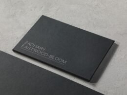 Schwarze Visitenkarte liegt mittig auf hellem Holztisch, minimalistisches Design für Geschäftspräsentationen.