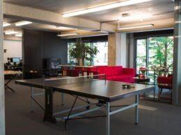 Ping Pong Tisch in einem modernen Büro mit heller Einrichtung und Arbeitsplätzen im Hintergrund