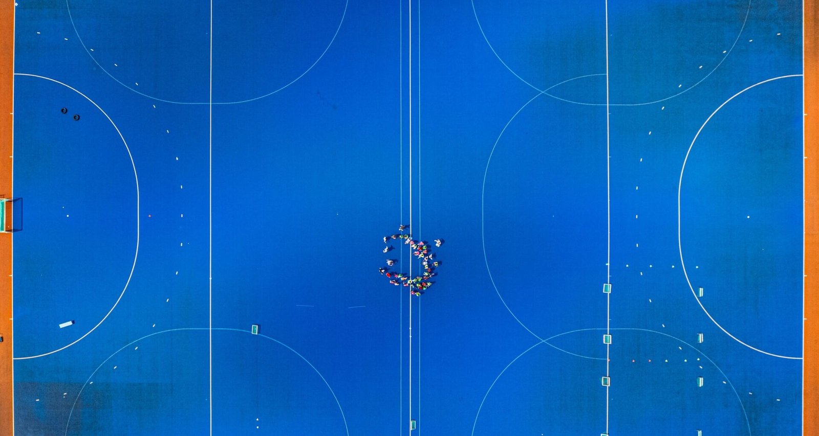 Überkopfaufnahme eines Basketballplatzes mit klaren Linien und Spielfeldmarkierungen auf geteilter Fläche.
