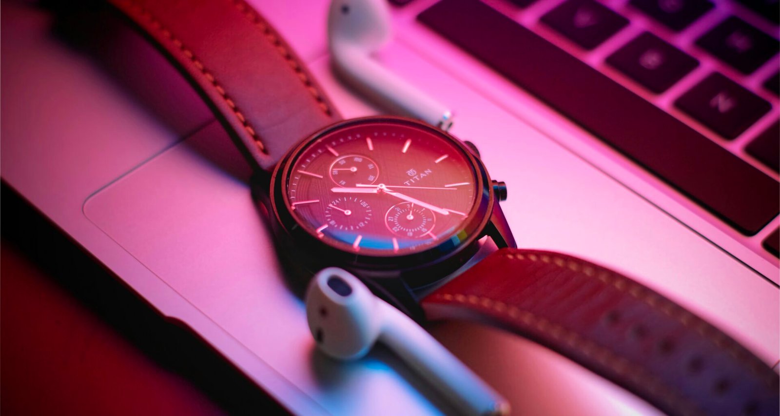 Nahaufnahme einer klassischen Armbanduhr, die auf einem modernen Laptop liegt – Fokus auf Zeitmanagement am Arbeitsplatz.