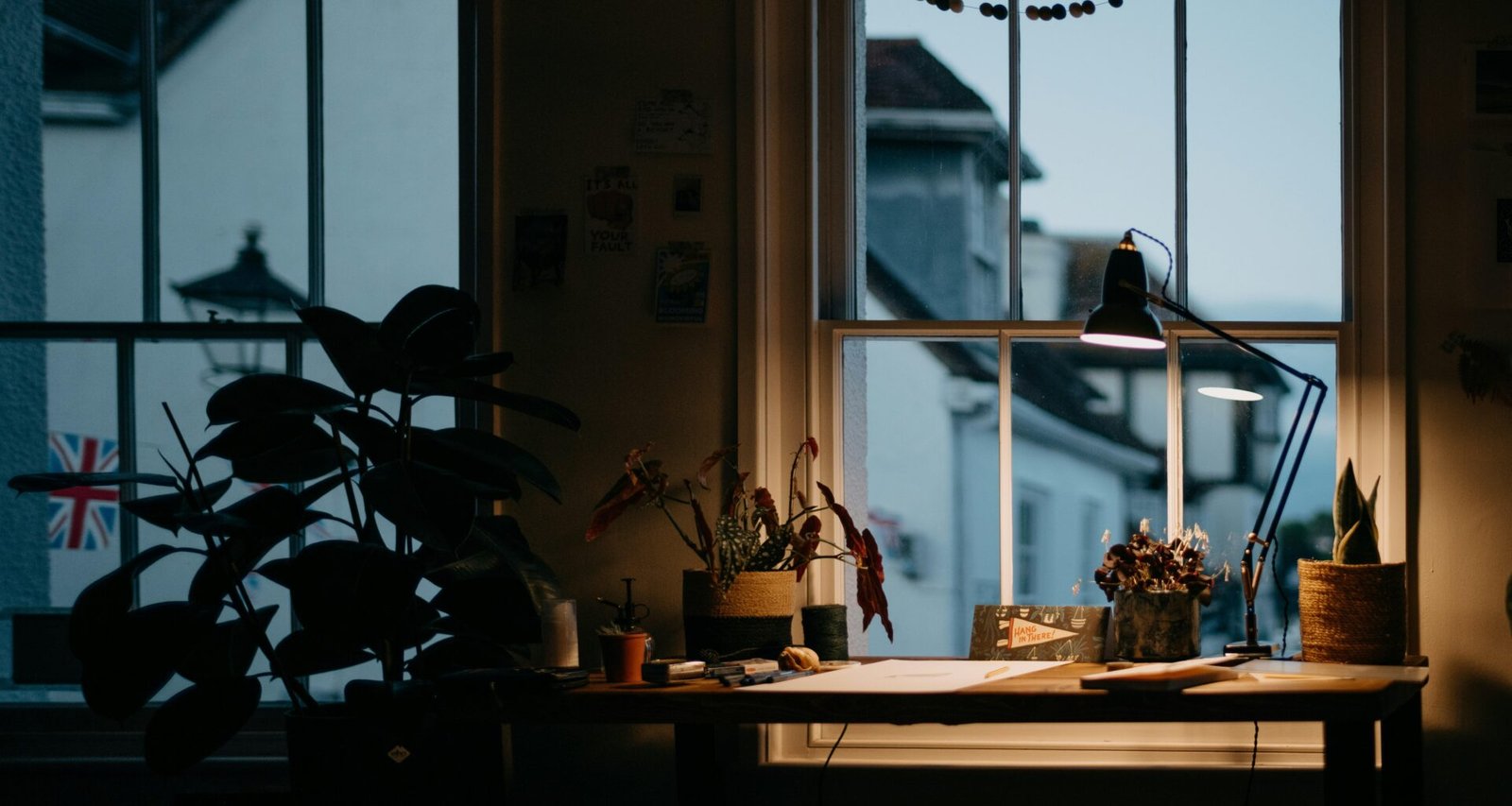 Ein Blumenstrauß in einer Vase steht auf einem Tisch direkt neben einem großen Fenster in einem hellen Raum.
